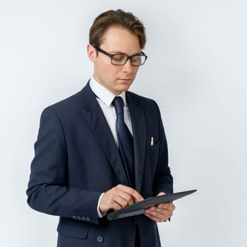 Portrait of a businessman in a blue suit holding an electronic tablet on a white background. Business and finance concept