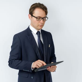 Portrait of a businessman in a blue suit holding an electronic tablet on a white background. Business and finance concept