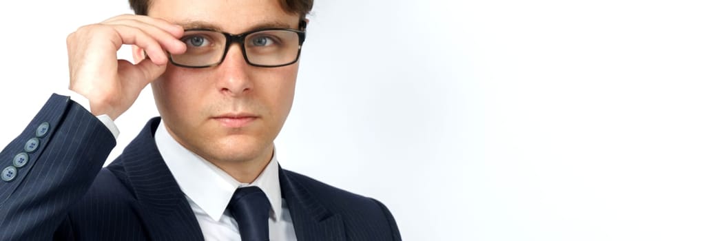 Portrait of a businessman in a blue suit, who adjusts his glasses. White background. Business and finance concept