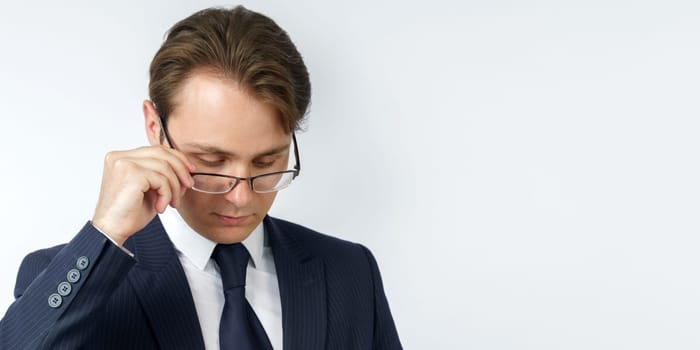 Portrait of a businessman in a blue suit, who adjusts his glasses. White background. Business and finance concept