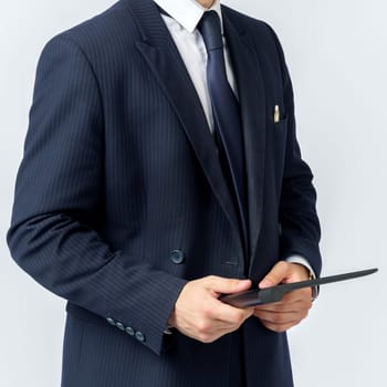 Portrait of a businessman in a blue suit holding an electronic tablet on a white background. Business and finance concept