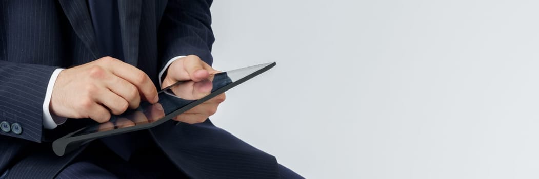 Portrait of a businessman in a blue suit holding an electronic tablet on a white background. Business and finance concept