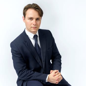 A portrait of a businessman in a blue suit who is clutching his hands. White background. Business and finance concept