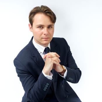 A portrait of a businessman in a blue suit who is clutching his hands. White background. Business and finance concept