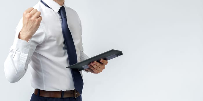 Portrait of a businessman raised his hand clenched into a fist, in the other hand an electronic tablet. No face visible. White background. Business and finance concept