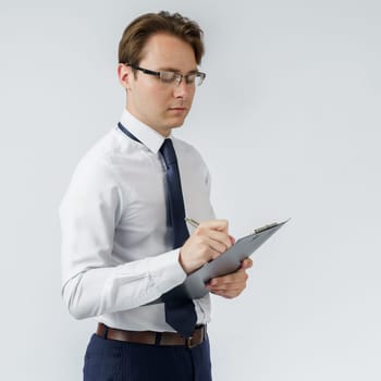 Portrait of a businessman who stands and writes down on a tablet. White background. Business and finance concept