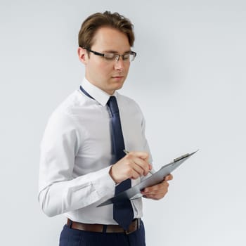 Portrait of a businessman who stands and writes down on a tablet. White background. Business and finance concept