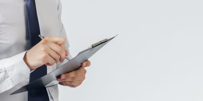 Businessman in a blue suit holds a folder in his hands on a white background. No face visible. Business and finance concept