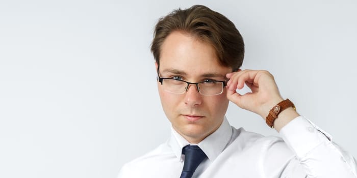 Portrait of a businessman adjusting his glasses. White background. Business and finance concept