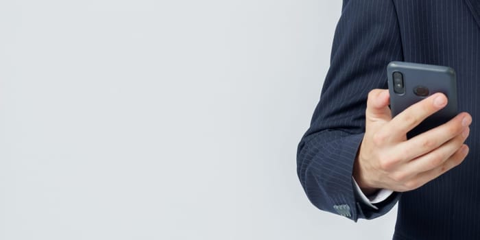 Businessman holds a mobile phone in his hands on a white background. The face is not visible. Business and finance concept