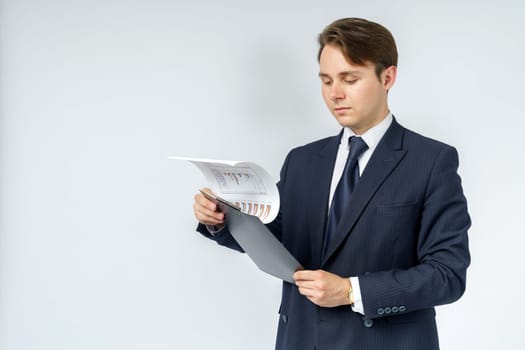 A businessman in a blue suit holds a folder in his hands and reads reports on a white background. Business and finance concept