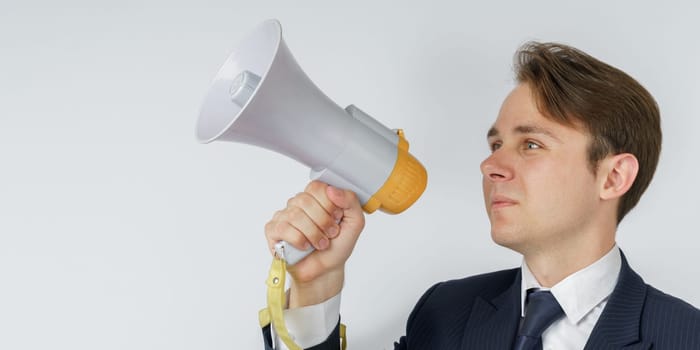 A businessman speaks into a loudspeaker. White background. Business and finance concept