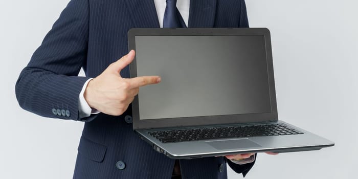 A businessman holds a laptop, the other hand shows the screen. White background. No face visible. Business and finance concept