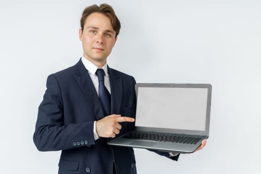 A businessman holds a laptop, the other hand shows the screen. White background. Business and finance concept