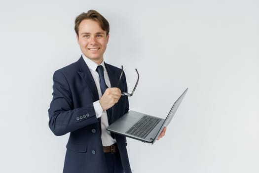 Portrait of a businessman who is holding a laptop and glasses. White background. Business and finance concept