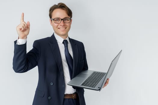 The businessman holds a laptop, the other hand shows a gesture. White background. Business and finance concept