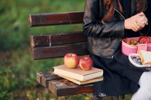 Close up view of couch with schoolgirl, books and apples.