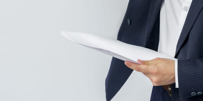 A businessman holds documents in his hands, his face is not visible. White background. Business and finance concept