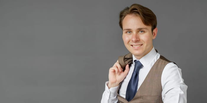 Portrait of a businessman who looks into the camera and holds a jacket over his shoulder. Gray background. Business and finance concept