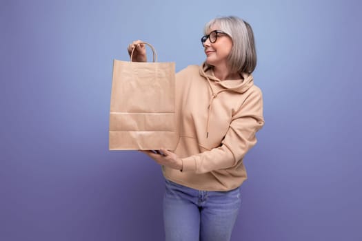 mature 60s business woman with gray hair holding social security package on studio background with copy space.