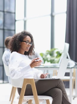 young attractive african american woman in the office sitting at a laptop