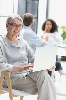 mature woman sitting with laptop looking at camera.