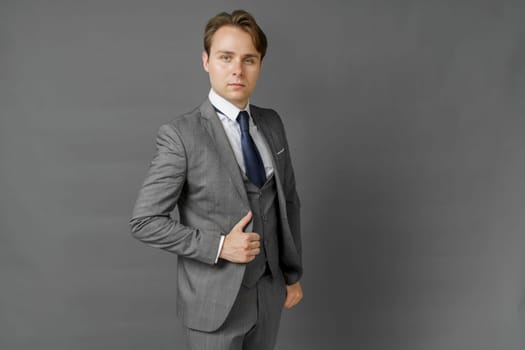 Portrait of a businessman in a suit looking at the camera. Gray background. Business and finance concept