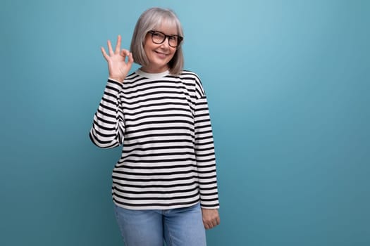 business woman 60s of age with gray hair shows joy and happiness on a bright studio background.