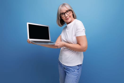 middle age business. a middle-aged woman with gray hair masters a remote profession on a computer in a studio background with copy space.