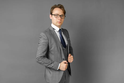 Portrait of a businessman in a suit looking at the camera. Gray background. Business and finance concept