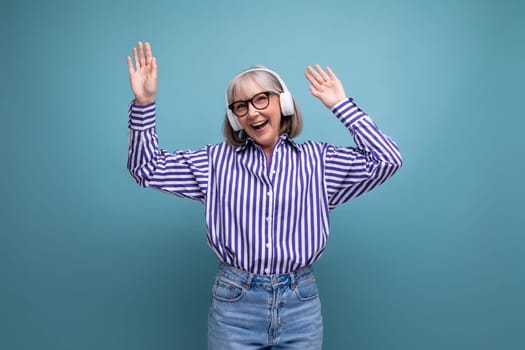 happy middle aged woman with gray hair with headphones on bright studio background.