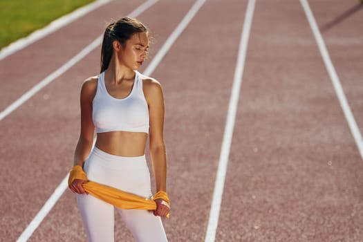 Holding streching equipment. Young woman in sportive clothes is exercising outdoors.