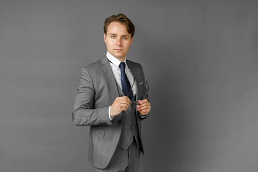 Portrait of a businessman in a suit looking at the camera. Gray background. Business and finance concept