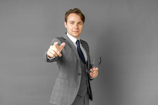 Portrait of a businessman in a suit that extended his hand forward. Gray background. Business and finance concept