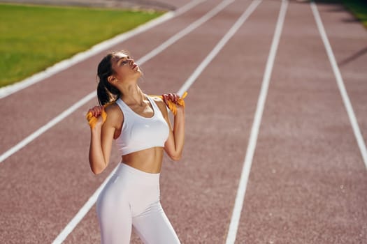 On the running track. Young woman in sportive clothes is exercising outdoors.