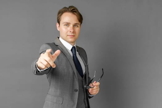 Portrait of a businessman in a suit that extended his hand forward. Gray background. Business and finance concept