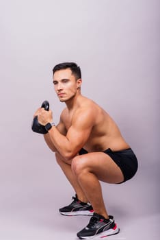 Hispanic male athlete working out with kettlebell on a grey background. Crossfit workout theme.