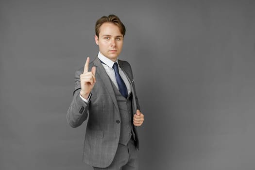 Portrait of a businessman in a suit that extended his hand forward. Gray background. Business and finance concept