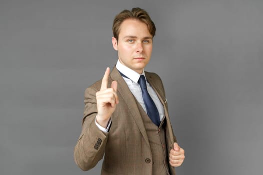 Portrait of a businessman in a suit that extended his hand forward. Gray background. Business and finance concept