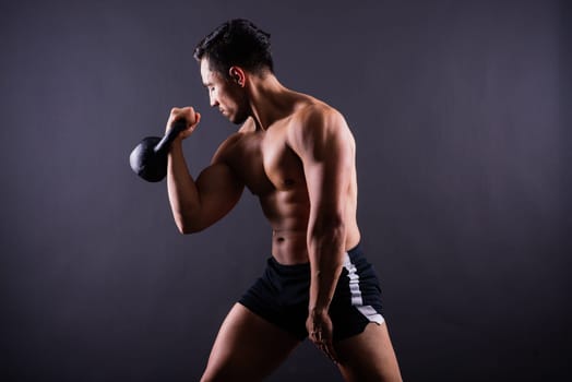 Hispanic male athlete working out with kettlebell on a grey background. Crossfit workout theme.