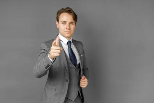 Portrait of a businessman in a suit that extended his hand forward. Gray background. Business and finance concept