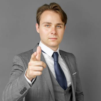 Portrait of a businessman in a suit that extended his hand forward. Gray background. Business and finance concept