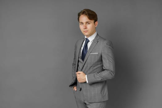 Portrait of a businessman in a suit looking at the camera. Gray background. Business and finance concept