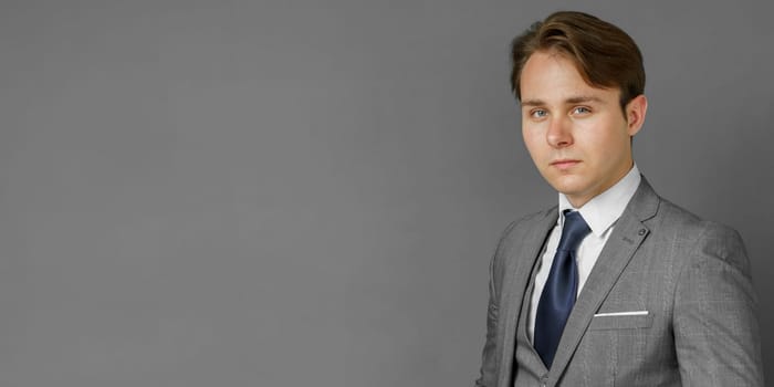 Portrait of a businessman in a suit looking at the camera. Gray background. Business and finance concept