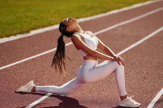 Stretching legs. Young woman in sportive clothes is exercising outdoors.