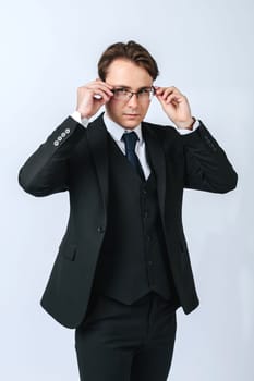 Business and finance concept. A man in a black suit adjusts his glasses. Light background