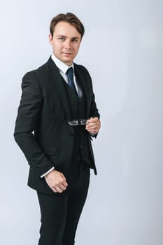 Business and finance concept. A man in a black suit holds glasses in his hands. Light background