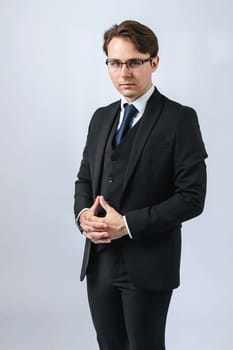 Business and finance concept. Portrait of a businessman in a black suit with glasses. Light background
