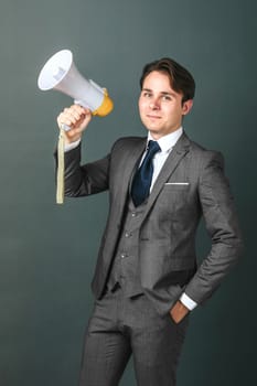 Business and finance concept. Portrait of a businessman who holds a megaphone in his hands. Light background
