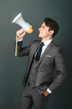 Business and finance concept. Portrait of a businessman who holds a megaphone in his hands. Light background